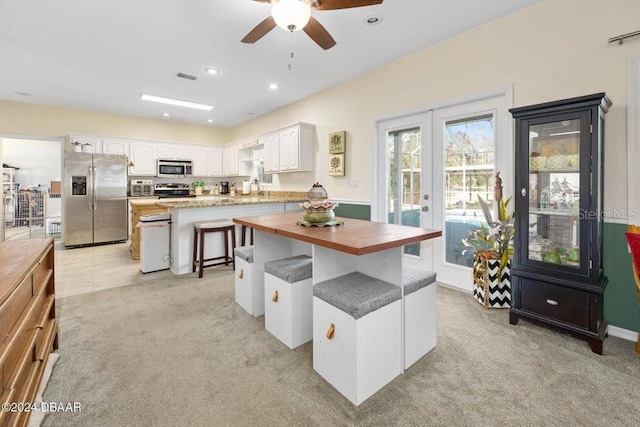 kitchen with french doors, a kitchen breakfast bar, a kitchen island, stainless steel appliances, and white cabinets