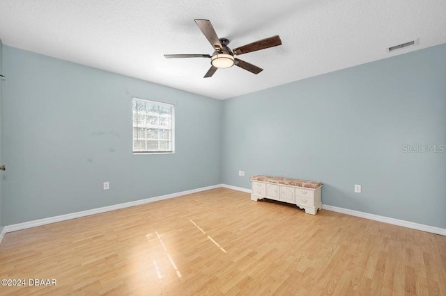 unfurnished room with ceiling fan, a textured ceiling, and light wood-type flooring