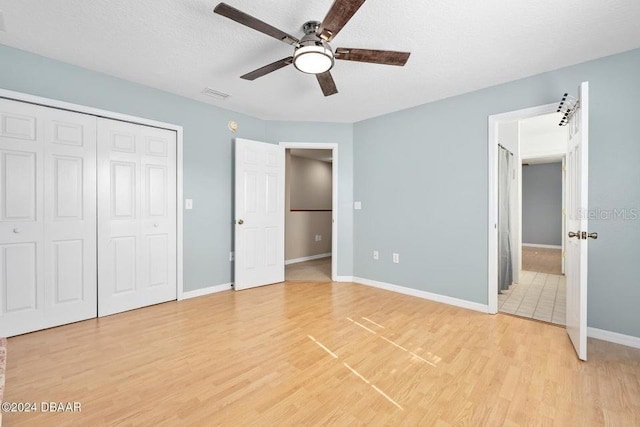 unfurnished bedroom featuring a textured ceiling, light hardwood / wood-style flooring, a closet, and ceiling fan