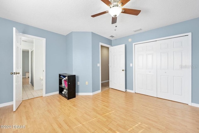 unfurnished bedroom with light hardwood / wood-style flooring, a textured ceiling, ceiling fan, and a closet