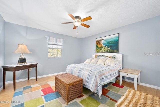 bedroom with a textured ceiling, light hardwood / wood-style floors, and ceiling fan