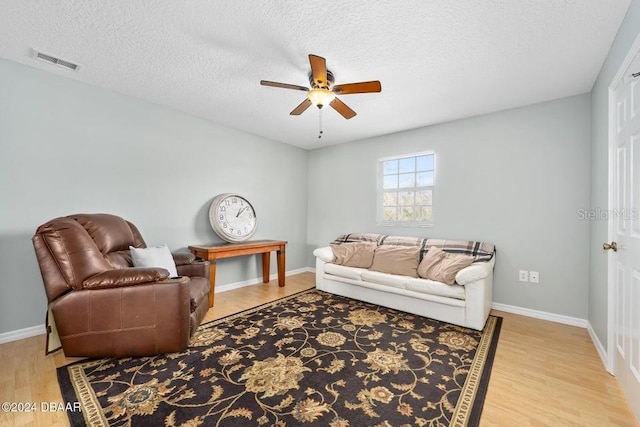 living room with hardwood / wood-style flooring, ceiling fan, and a textured ceiling