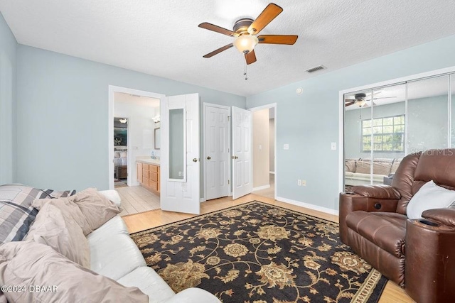 living room with ceiling fan, light hardwood / wood-style floors, and a textured ceiling