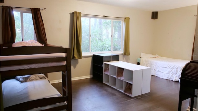 bedroom with dark hardwood / wood-style flooring and multiple windows