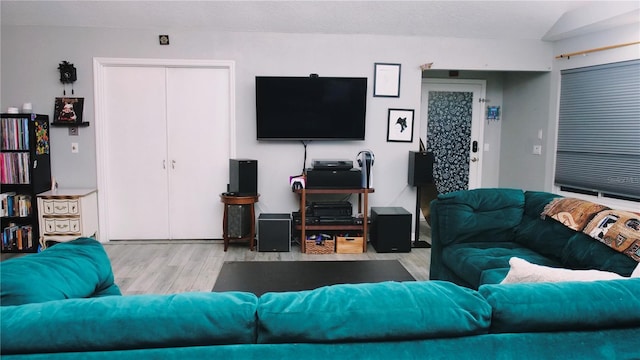 living room with a textured ceiling, light hardwood / wood-style flooring, and vaulted ceiling