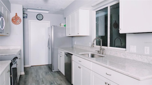 kitchen with light stone counters, stainless steel appliances, sink, light hardwood / wood-style flooring, and white cabinets