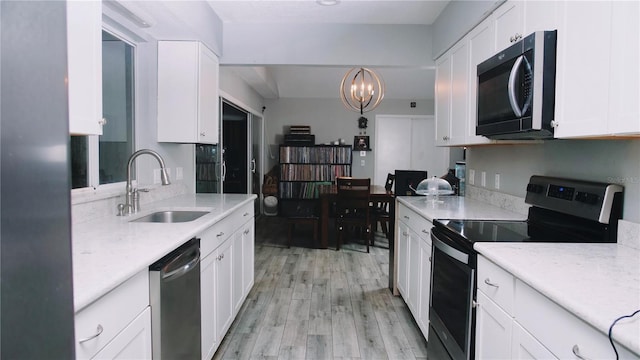 kitchen featuring white cabinets, decorative light fixtures, stainless steel appliances, and sink