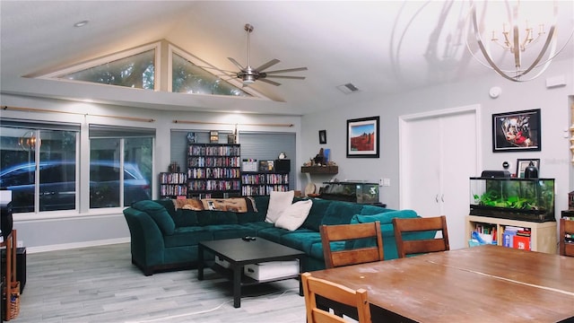 living room with ceiling fan with notable chandelier, hardwood / wood-style flooring, and vaulted ceiling