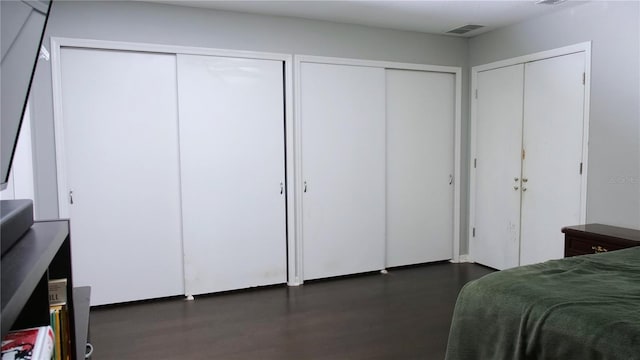 bedroom featuring dark hardwood / wood-style flooring and two closets