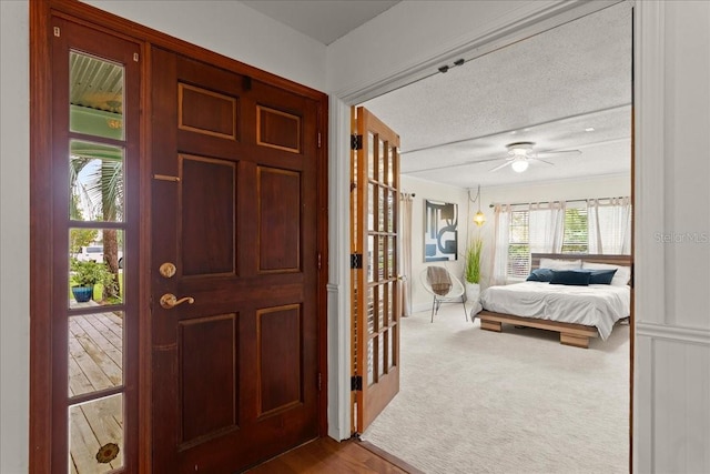 foyer entrance featuring ceiling fan, light carpet, and a textured ceiling