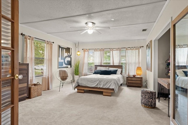 bedroom featuring carpet flooring, a textured ceiling, ceiling fan, and crown molding