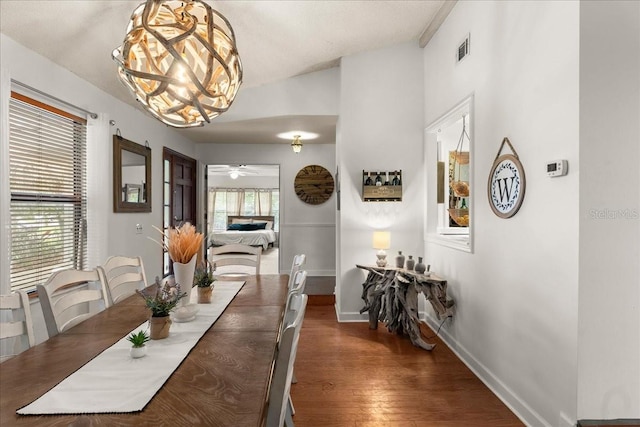 dining space featuring ceiling fan with notable chandelier, dark hardwood / wood-style flooring, a wealth of natural light, and lofted ceiling