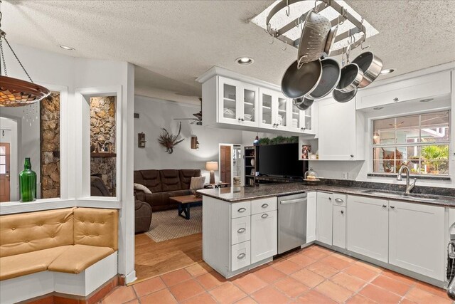 kitchen with a textured ceiling, dishwasher, white cabinetry, and sink