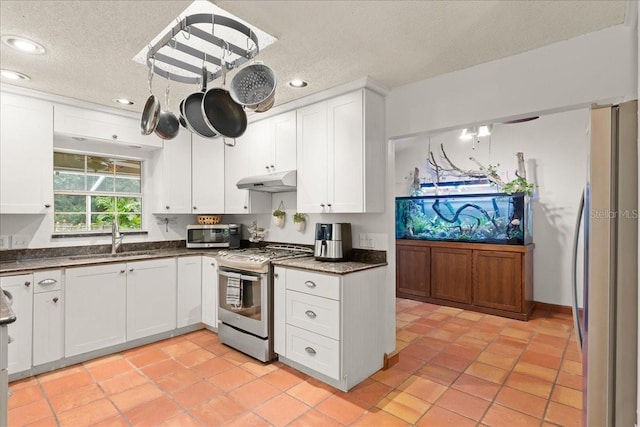 kitchen featuring white cabinets, appliances with stainless steel finishes, a textured ceiling, and sink