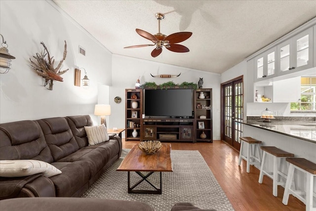 living room with hardwood / wood-style floors, lofted ceiling, a textured ceiling, and french doors