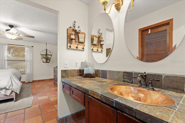 bathroom featuring ceiling fan, tile patterned flooring, a textured ceiling, decorative backsplash, and vanity