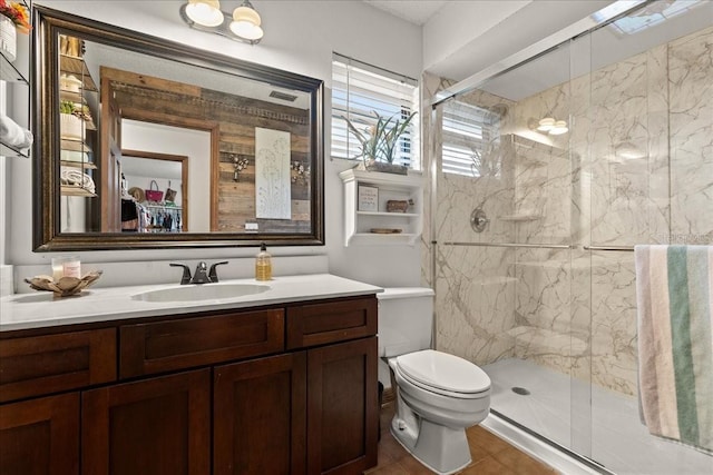 bathroom with tile patterned floors, vanity, an enclosed shower, and toilet