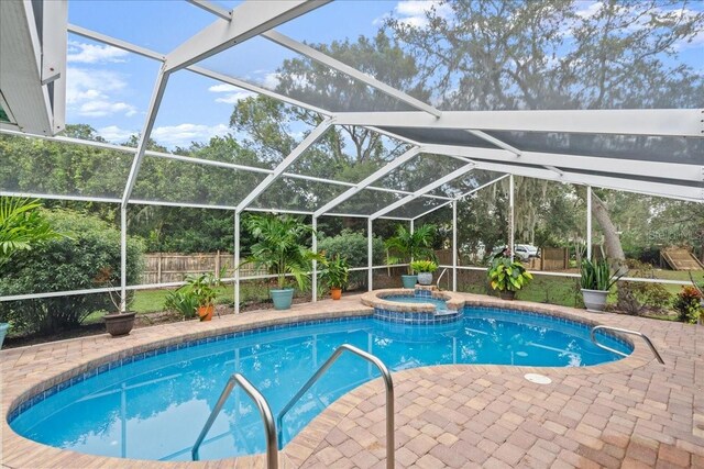 view of pool with a lanai, a patio area, and an in ground hot tub