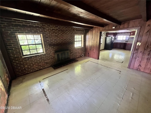 unfurnished living room with plenty of natural light, wood walls, and a fireplace