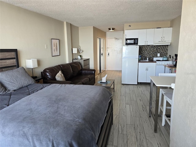 bedroom with sink, white fridge, a textured ceiling, and light wood-type flooring