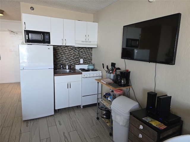 kitchen featuring a textured ceiling, sink, white cabinets, and white appliances