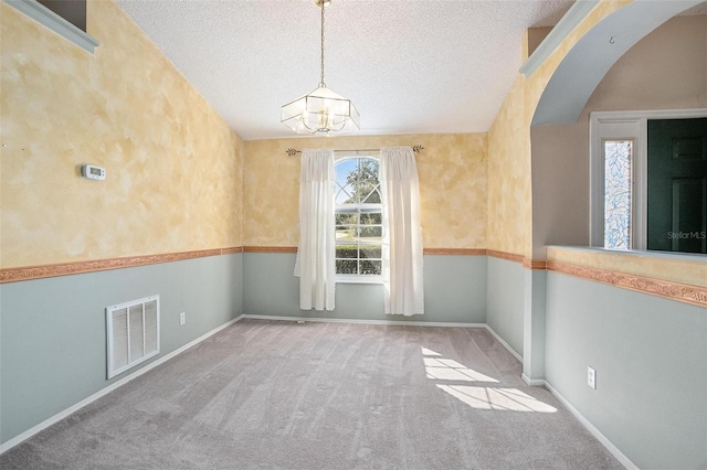 unfurnished room with a textured ceiling, light colored carpet, and an inviting chandelier