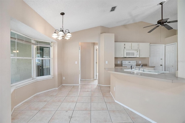 kitchen with hanging light fixtures, lofted ceiling, white appliances, white cabinets, and ceiling fan with notable chandelier