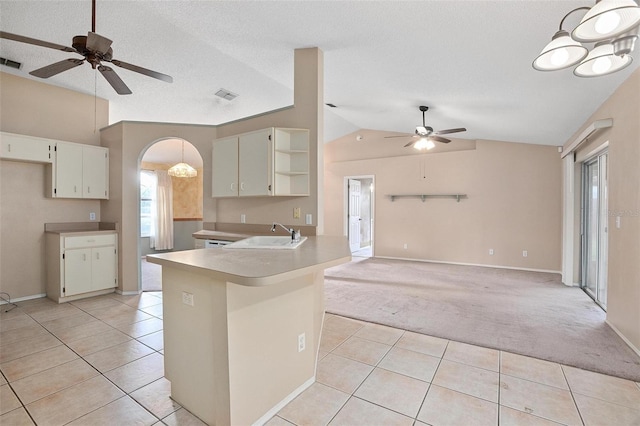 kitchen featuring pendant lighting, ceiling fan, kitchen peninsula, and vaulted ceiling