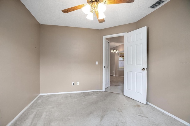 carpeted spare room featuring a textured ceiling and ceiling fan with notable chandelier