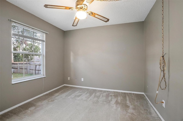 spare room with a textured ceiling, carpet floors, and ceiling fan