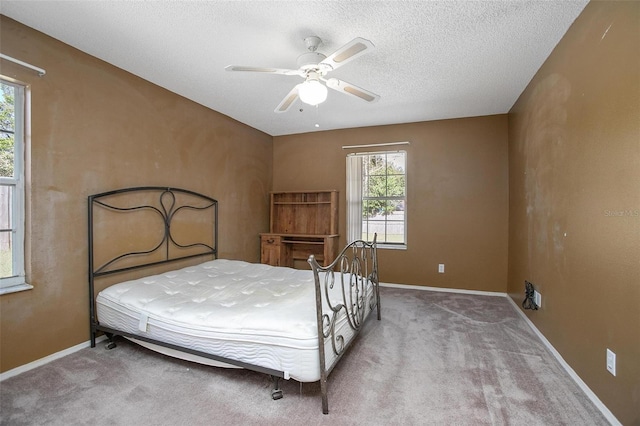 carpeted bedroom featuring ceiling fan and a textured ceiling