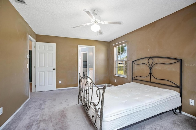 carpeted bedroom with ceiling fan and a textured ceiling