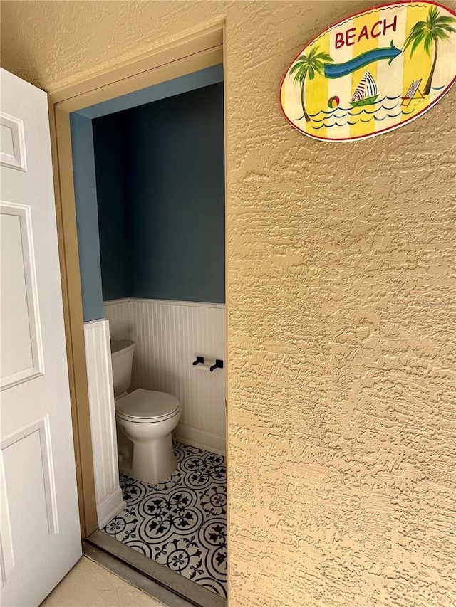 bathroom featuring toilet and a wainscoted wall
