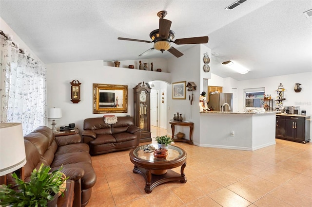 living room with a textured ceiling, ceiling fan, light tile patterned floors, and lofted ceiling