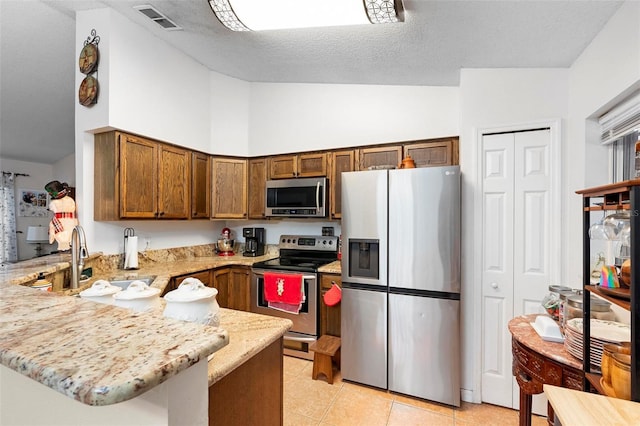 kitchen with a kitchen breakfast bar, kitchen peninsula, light tile patterned floors, and stainless steel appliances