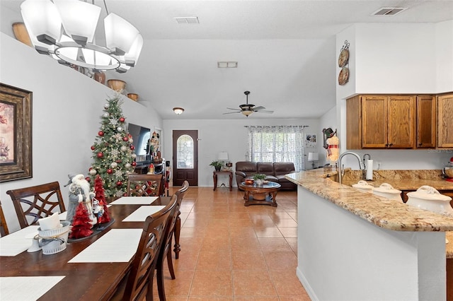 tiled dining area with ceiling fan with notable chandelier