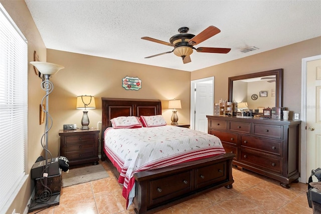 tiled bedroom with ceiling fan and a textured ceiling