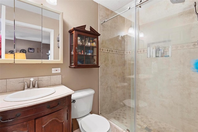 bathroom with vanity, a shower with shower door, and toilet