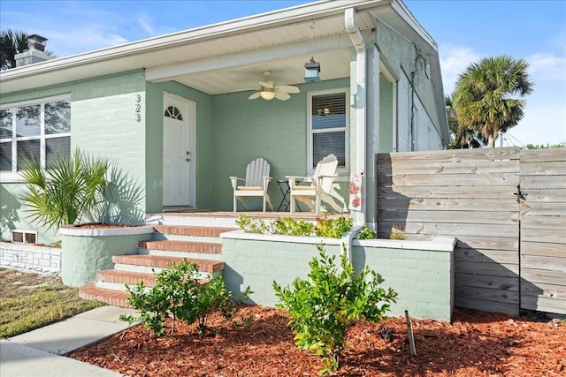 view of exterior entry with ceiling fan and covered porch