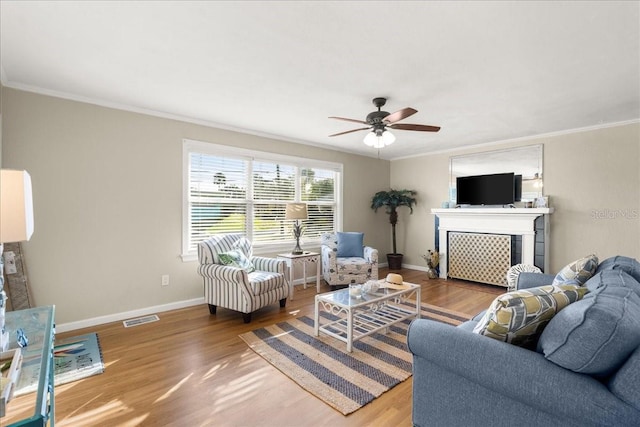 living room with hardwood / wood-style flooring, ceiling fan, and ornamental molding