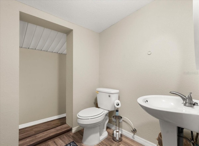 bathroom featuring wood-type flooring, a textured ceiling, and toilet