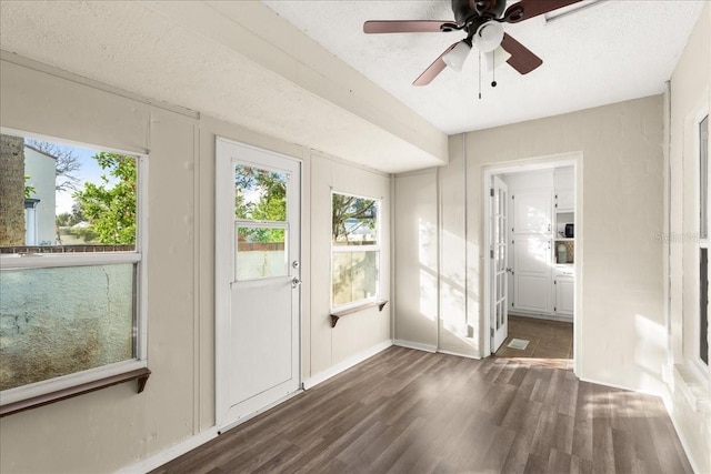 doorway to outside featuring ceiling fan, dark wood-type flooring, and a textured ceiling