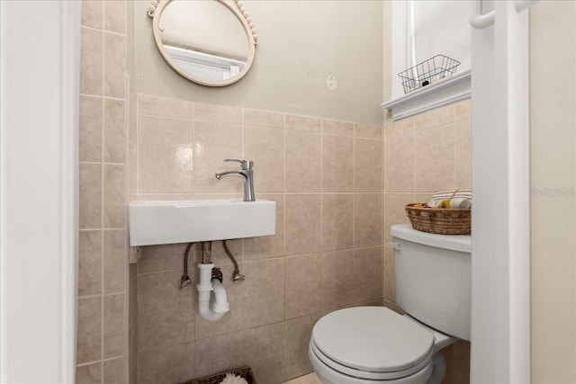 bathroom featuring toilet, tile walls, and sink