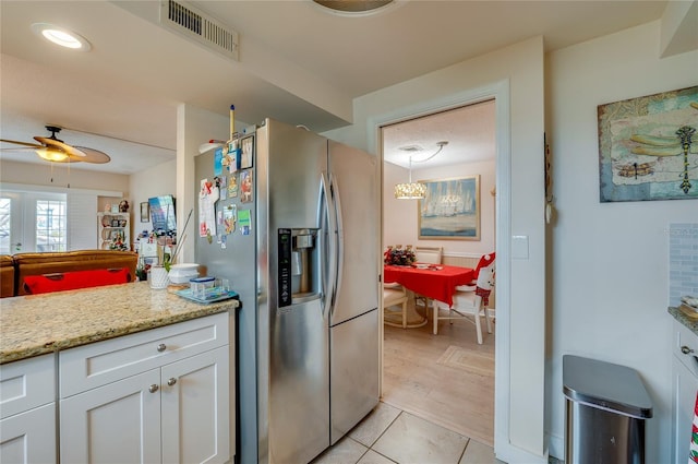 kitchen featuring white cabinetry, stainless steel fridge, ceiling fan, light stone countertops, and pendant lighting