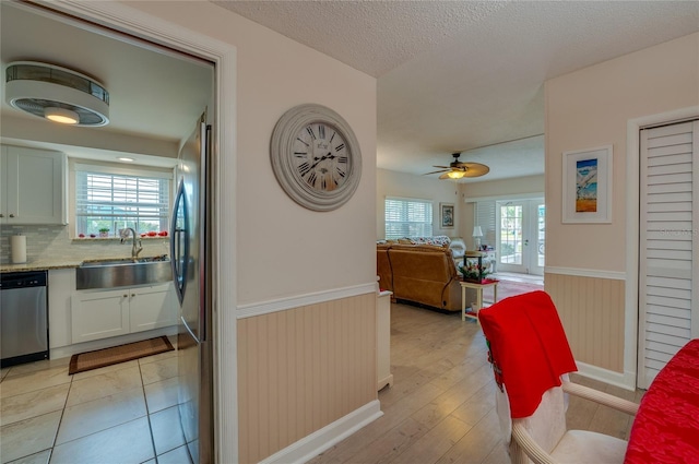 kitchen with a wealth of natural light, white cabinets, appliances with stainless steel finishes, sink, and ceiling fan