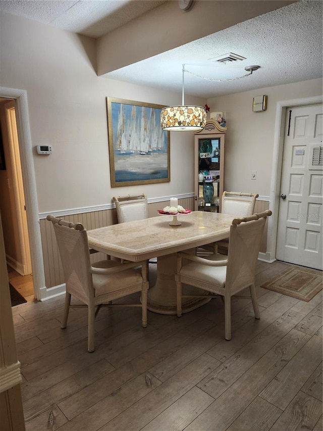 dining area with a textured ceiling and hardwood / wood-style flooring