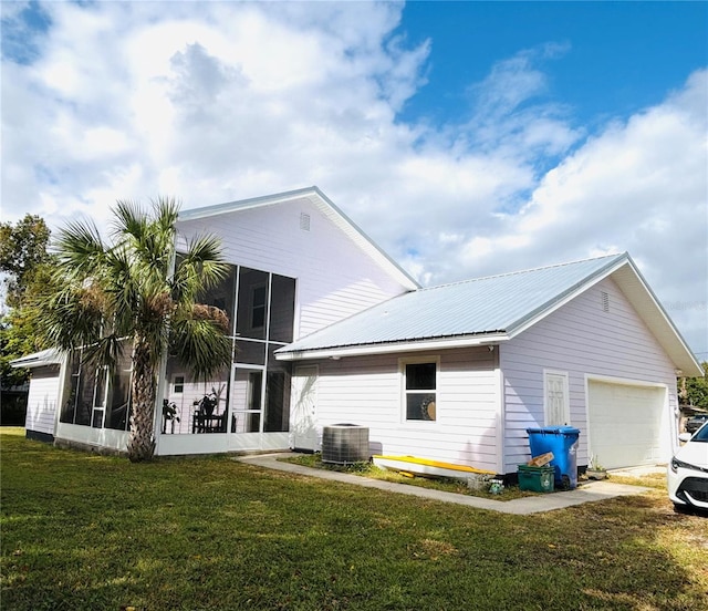 rear view of property with a yard, central air condition unit, a garage, and a sunroom