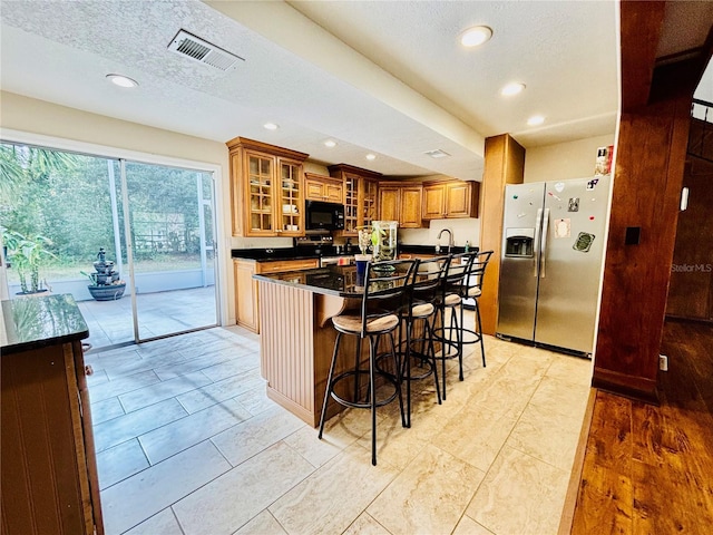 kitchen with a center island, sink, a textured ceiling, appliances with stainless steel finishes, and a kitchen bar