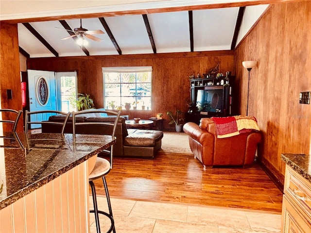 living room with light wood-type flooring, vaulted ceiling with beams, and wood walls