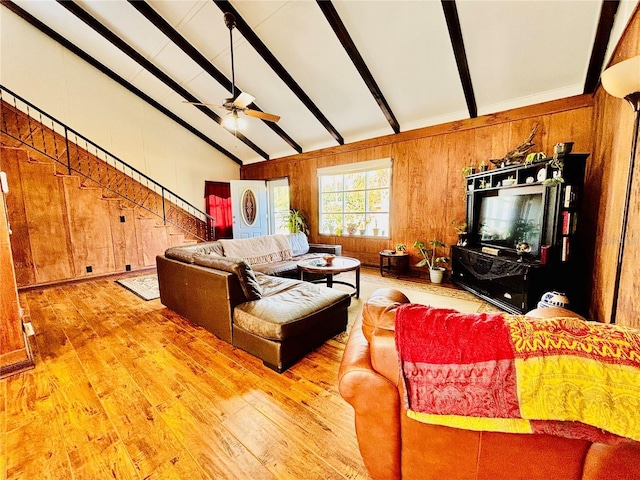 living room featuring wood walls, lofted ceiling with beams, ceiling fan, and wood-type flooring